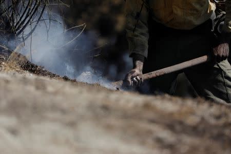 A firefighter works to put out hot spots during the Wilson Fire near Mount Wilson in the Angeles National Forest in Los Angeles, California, U.S. October 17, 2017. REUTERS/Mario Anzuoni