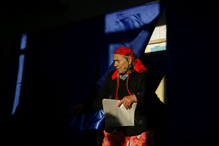 A woman exits a polling booth while holding a ballot for parliamentary elections, in Sintesti, Ilfov county, Romania, December 11, 2016. Inquam Photos/Adel Al-Haddad/via REUTERS