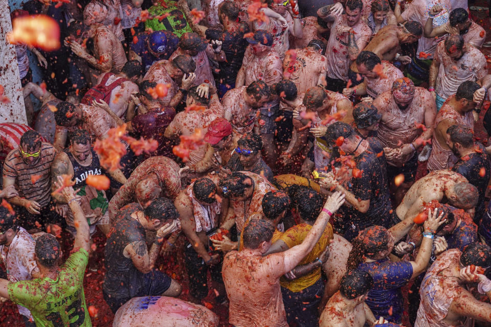 Revellers throw tomatoes at each other during the annual "Tomatina", tomato fight fiesta in the village of Bunol near Valencia, Spain, Wednesday, Aug. 31, 2022. The tomato fight took place once again following a two-year suspension owing to the coronavirus pandemic. (AP Photo/Alberto Saiz)