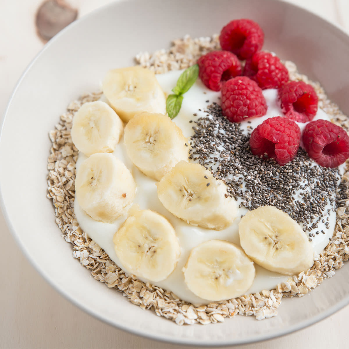 bowl of oats topped with bananas, raspberries, chia seeds