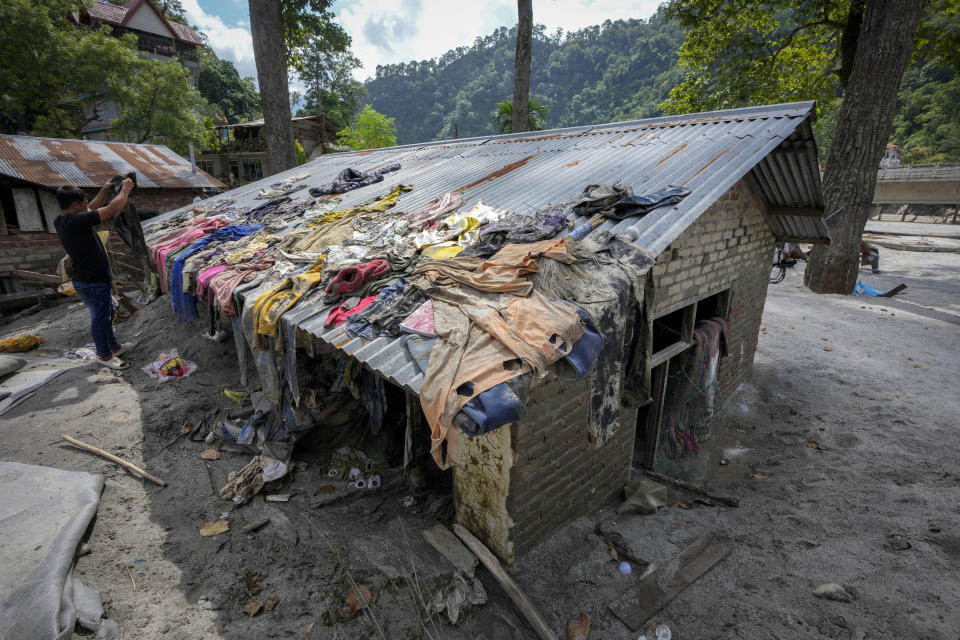 A flood affected man dries clothes on the roof of his previously submerged house along the Teesta river in Rongpo, east Sikkim, India, Sunday, Oct. 8. 2023. Rescuers continued to dig through slushy debris and ice-cold water in a hunt for survivors after a glacial lake burst through a dam in India’s Himalayan northeast, shortly after midnight Wednesday, washing away houses and bridges and forcing thousands to flee. (AP Photo/Anupam Nath)