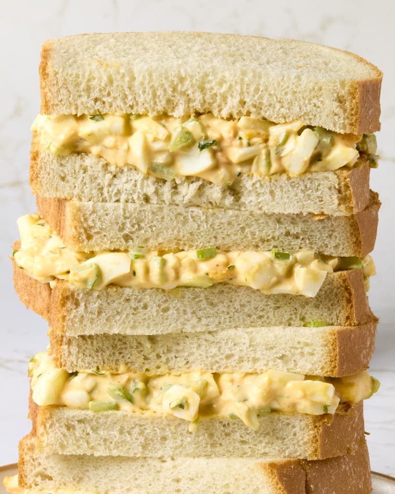 head on shot of four halves of an egg salad sandwich stacked on one another.