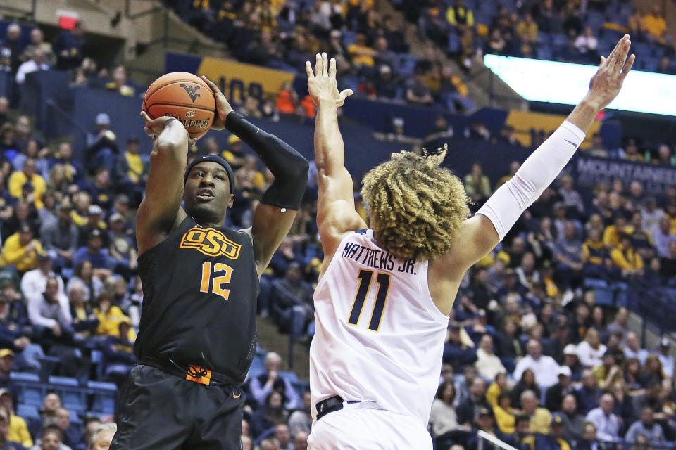 Oklahoma State forward Cameron McGriff (12) shoots as West Virginia forward Emmitt Matthews Jr. (11) defends during the first half of an NCAA college basketball game Tuesday, Feb. 18, 2020, in Morgantown, W.Va. (AP Photo/Kathleen Batten)