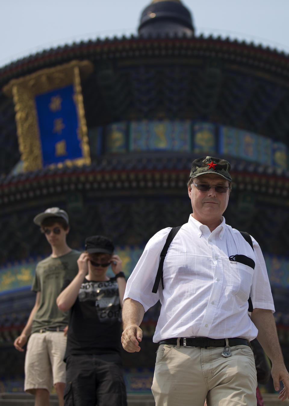 In this Wednesday, July 31, 2013 photo, a foreign tourist wears a communist hat as he and others visit the Temple of Heaven in Beijing. China's new tourism slogan "Beautiful China" has been criticized by industry experts who say it illustrates a marketing problem that has led to a weakness in growth in foreign visitors over the past few years. (AP Photo/Andy Wong)