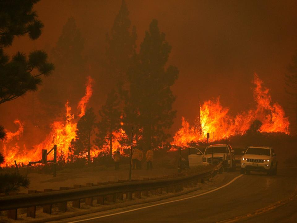 Flames rush uphill behind cars toward Meyers, California, in 2021.