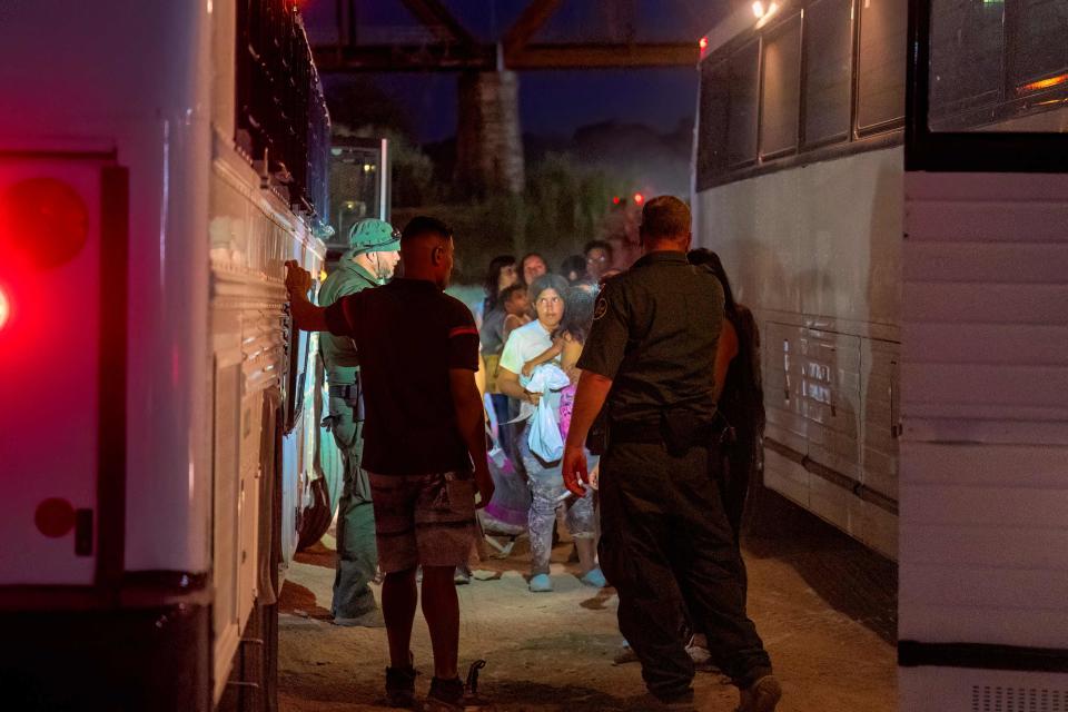 Border Patrol agents escort migrants onto a bus to be taken to a processing facility to begin their asylum-seeking process in Eagle Pass, Texas on June 25, 2023.