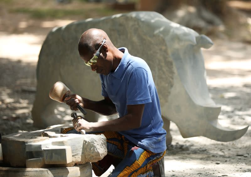 Zimbabwean sculptor Dominic Benhura works on a piece at his studio in Harare