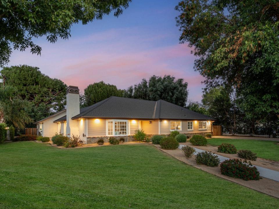 A house with a green lawn in front of a sunset.