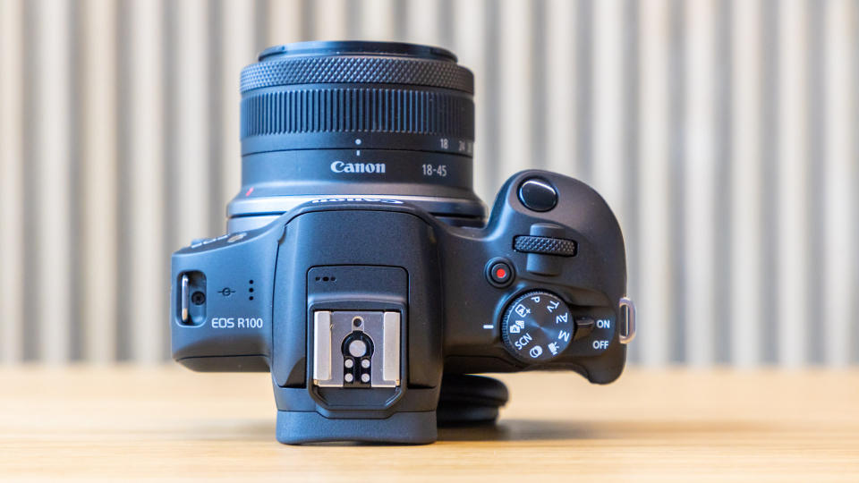 Canon EOS R100 camera on a table with a striped background