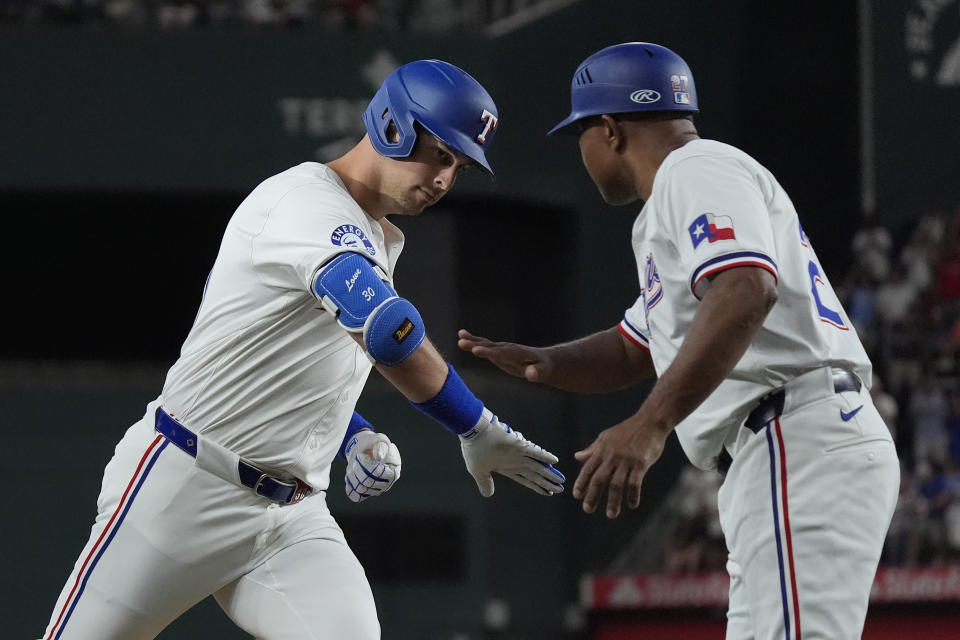 Texas Rangers Nathaniel Lowe, left, is congratulated by third base coach Tony Beasley (27) as Lowe rounds the bases after hitting a home run during the first inning of a baseball game against the San Diego Padres in Arlington, Texas, Tuesday, July 2, 2024. Rangers Josh Smith also scored on the play. (AP Photo/LM Otero)