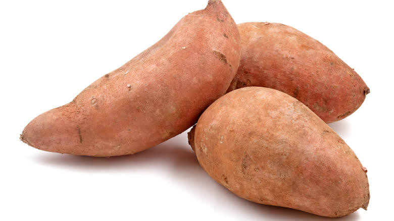 Three sweet potatoes against white