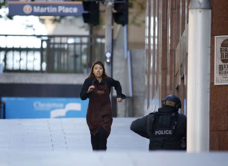 A hostage runs towards a police officer outside Lindt cafe, where other hostages are being held, in Martin Place in central Sydney December 15, 2014. REUTERS/Jason Reed