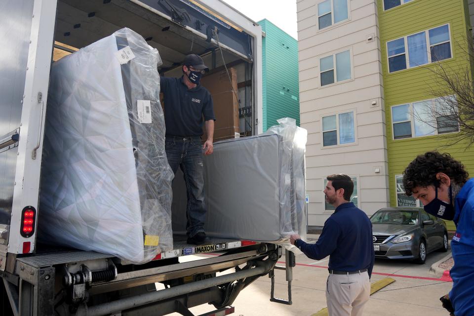 From left, Factory Mattress employee Derrick Maynard, Factory Mattress President Stephen Frey Jr. and employee Robert Escalera carry new mattresses Wednesday into the home of Rebecca Adamson and Chris Watkins. "This is our way of giving back to the community; they've always given back to us," Frey said.