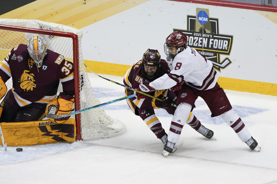 Massachusetts' Bobby Trivigno (8) sends the puck past Minnesota Duluth goaltender Zach Stejskal (35), before Garrett Wait, not seen, knocked it in for an overtime goal in an NCAA men's Frozen Four hockey semifinal in Pittsburgh, early Friday, April 9, 2021. Massachusetts won 3-2 and will face St. Cloud State in the championship game Saturday. (AP Photo/Keith Srakocic)