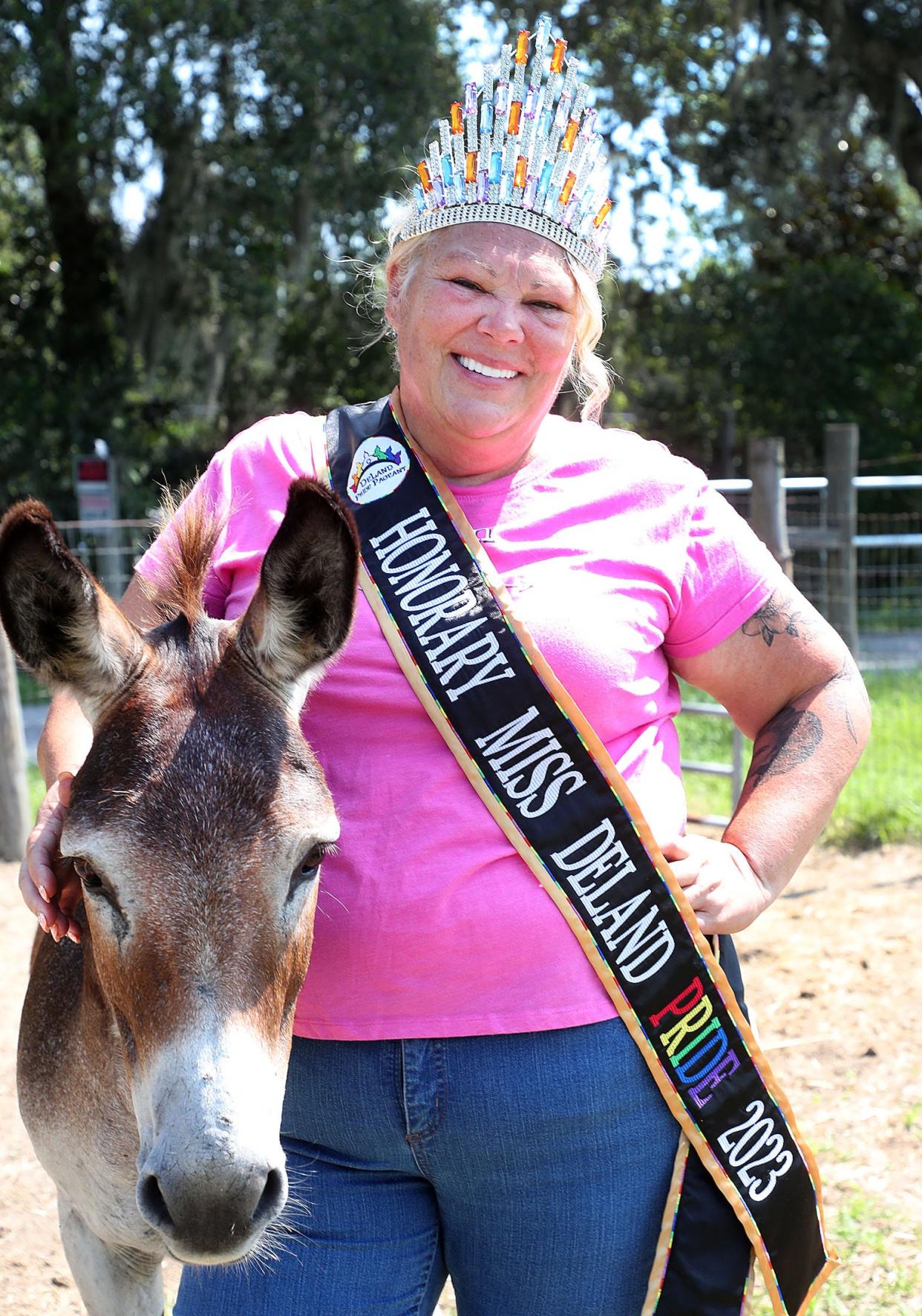Mary Taylor Green, who was named Honorary Miss DeLand Pride at this year's pageant, poses in her sash and crown alongside her donkey named Roger on her farm, Green Acres, in DeLand, on June 29.