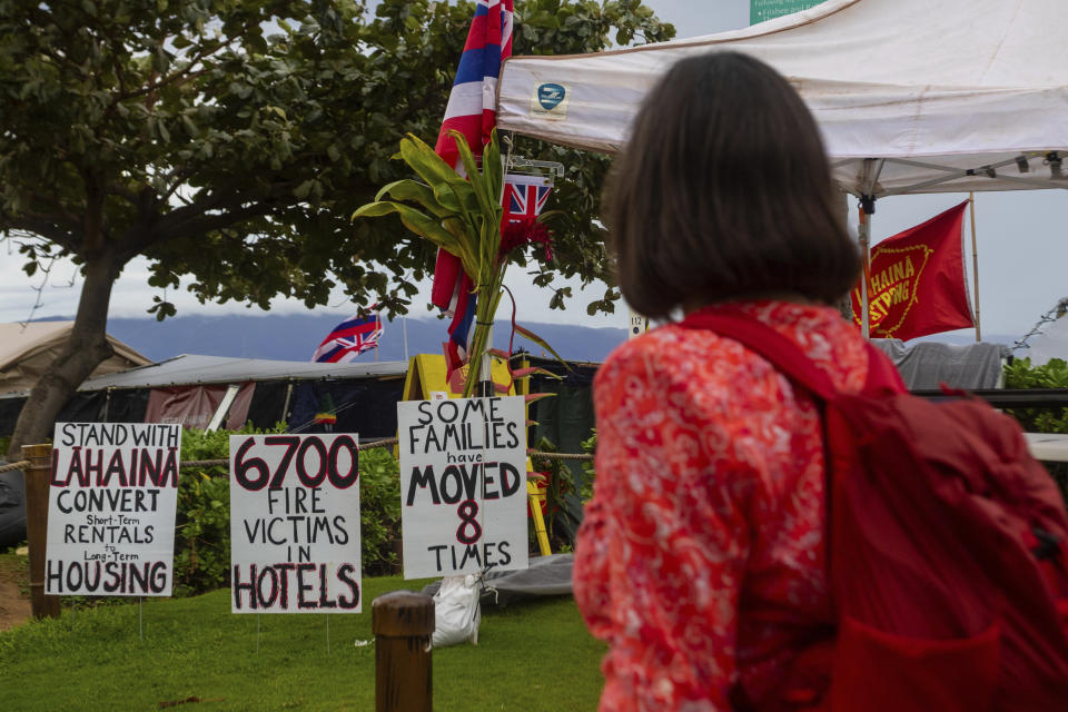 A tourist stops to read signs at the Lahaina Strong "Fish-in" on Friday, Dec. 1, 2023, in Lahaina, Hawaii. Lahaina Strong has set up a "Fish-in" to protest living accommodations for those displaced by the Aug. 8, 2023 wildfire, the deadliest U.S. wildfire in more than a century. More than four months after the fire, tensions are growing between those who want to welcome tourists back to provide jobs and those who feel the town isn't ready for a return to tourism. (AP Photo/Ty O'Neil)