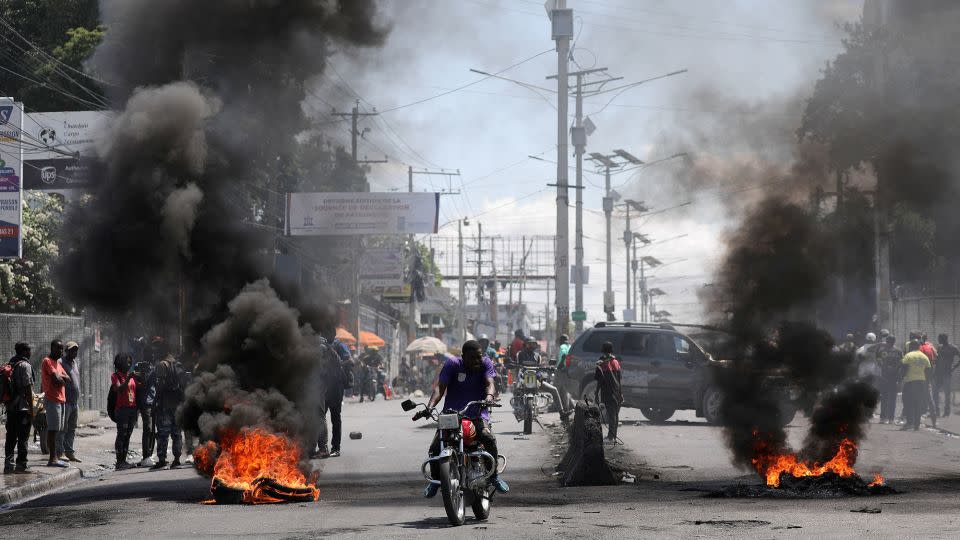 Motorists pass by a burning barricade during a protest in Port-au-Prince, Haiti, on March 7, 2024. - Ralph Tedy Erol/Reuters