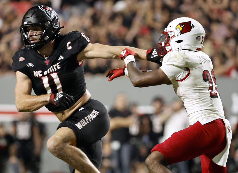 FILE - North Carolina State linebacker Payton Wilson (11) stiff-arms Louisville running back Isaac Guerendo, right, during the first half of an NCAA college football game in Raleigh, N.C., Sept. 29, 2023. Wilson has been selected by The Associated Press as the defensive player of the year for the Atlantic Coast Conference. (AP Photo/Karl B DeBlaker, File)