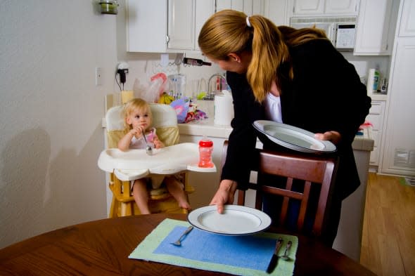 B158R4 Still in her office clothes a professional woman hurries to set the dinner table for her family in Lake Forest CA breadwi