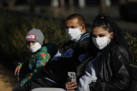 A family wearing face masks enjoy a sunny day at a playground in Prague, Czech Republic, Monday, March 23, 2020. Czech Republic has made it mandatory that all people must cover their mouths and noses in public to stem the spread of the novel coronavirus called COVID-19. Improvised methods such as a scarf or homemade mask are allowed. (AP Photo/Petr David Josek)