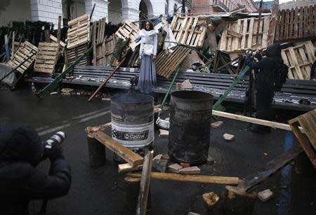 A model (C) poses at a barricade as she takes part in a photo shoot for an art project, at Independence Square in Kiev December 7, 2013. REUTERS/Stoyan Nenov