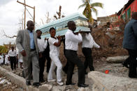 <p>People carry the coffin of a woman who died during Hurricane Matthew in front of destroyed houses in Jeremie, Haiti, October 11, 2016. (Carlos Garcia Rawlins/Reuters)</p>