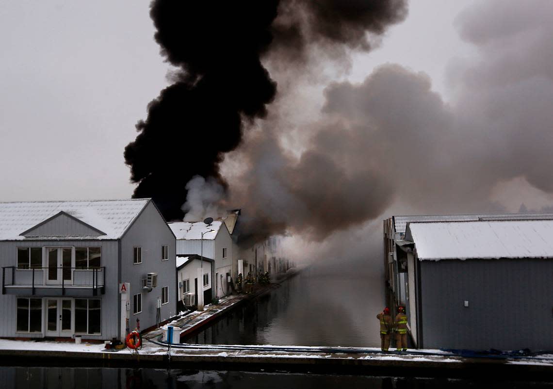 Thick black smoke billows into the sky early Wednesday morning as firefighters work to stop the spread of a boat house fire at the Clover Island Yacht Club in downtown Kennewick.