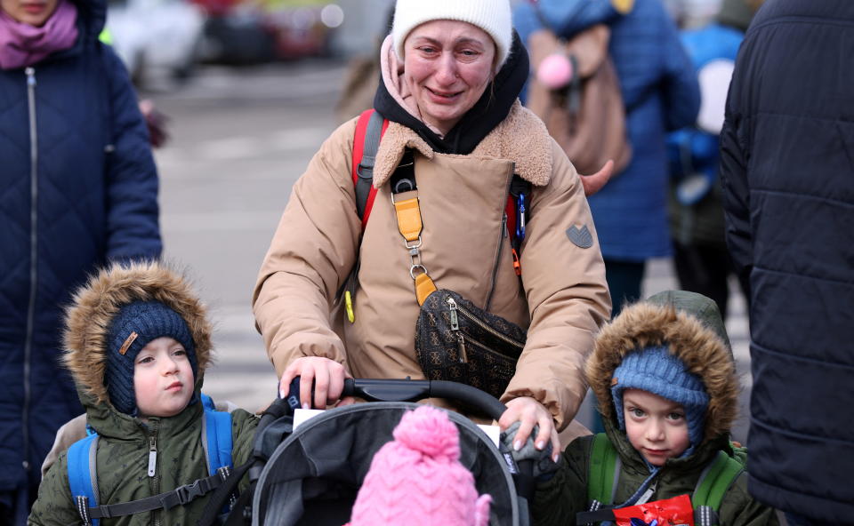 A crying woman walking with her children.