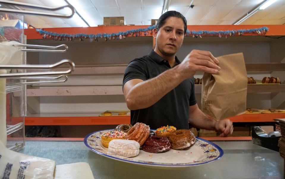 Gabriel Gutierrez, 30, stands behind the counter as he prepares to bag a couple of donuts inside the temporary Donut Villa location in southwest Detroit on Wednesday, March 29, 2023. 