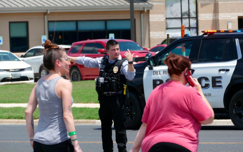 A law enforcement officer helps people cross the street at Uvalde Memorial Hospital - AP