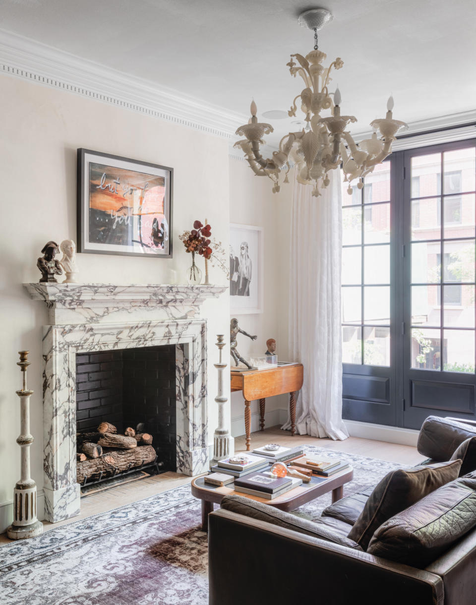 Cream painted living room with traditional coving, marble fireplace, antique rug and brown leather sofa