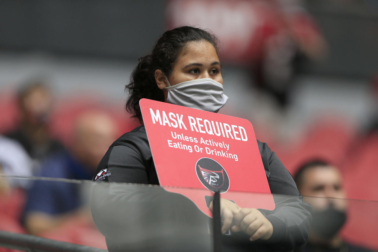 ATLANTA, GA - OCTOBER 25:  A stadium employee holds up a sign about wearing masks during the week 7 NFL game between the Atlanta Falcons and the Detroit Lions on October 25, 2020 at Mercedes-Benz Stadium in Atlanta, Georgia.  (Photo by David John Griffin/Icon Sportswire via Getty Images)