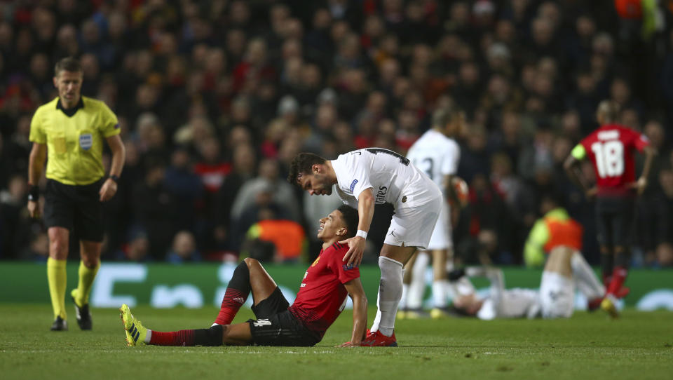 Manchester United's Jesse Lingard, lies injured as Paris Saint Germain's Juan Bernat leans over to help during the Champions League round of 16 soccer match between Manchester United and Paris Saint Germain at Old Trafford stadium in Manchester, England, Tuesday, Feb. 12,2019.(AP Photo/Dave Thompson)