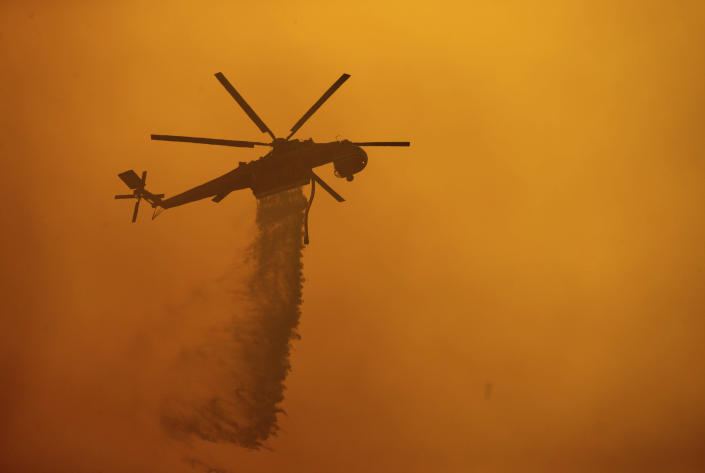 A helicopter drops water on the Fawn Fire burning north of Redding in Shasta County, Calif., on Thursday, Sept. 23, 2021. (AP Photo/Ethan Swope)