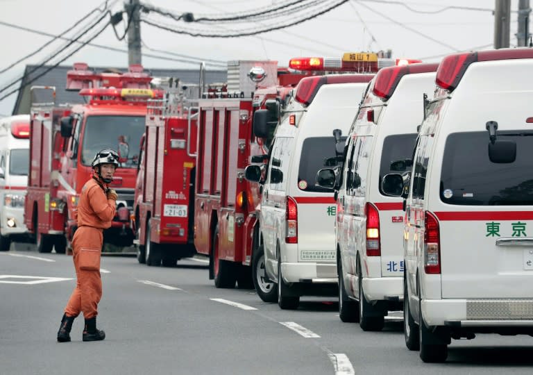 A rescue worker stands by beside ambulances near the Tsukui Yamayuri En care centre