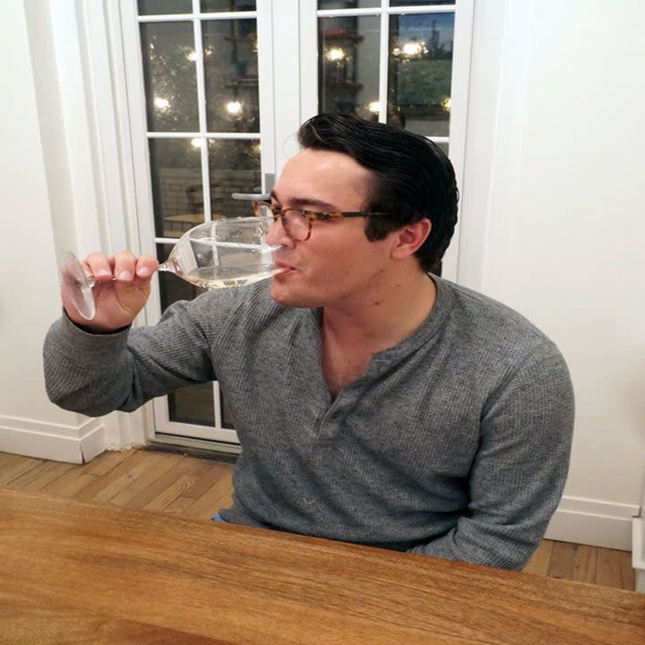 A man drinking a glass of white wine