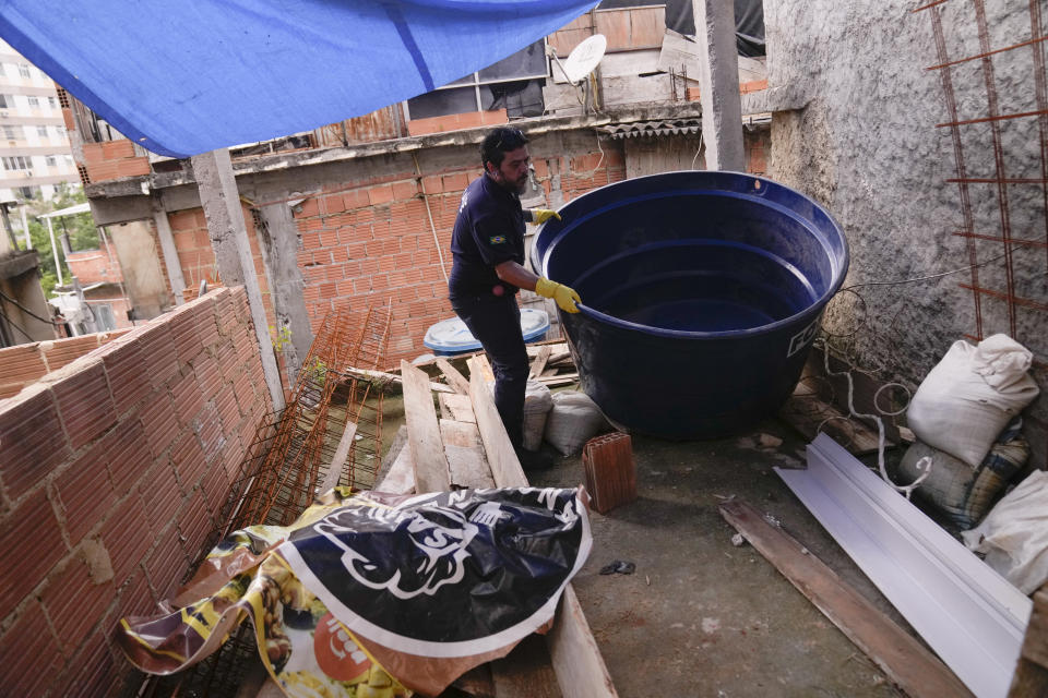 A municipal health worker empties a home's water container where mosquitos can breed, in an effort to eradicate the Aedes aegypti mosquito which can spread dengue fever, in the Tabajaras favela of the Copacabana neighborhood in Rio de Janeiro, Brazil, Wednesday, Feb. 7, 2024. (AP Photo/Silvia Izquierdo)