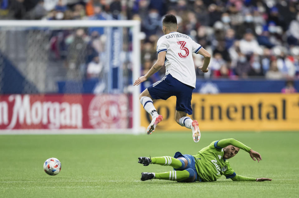 Vancouver Whitecaps' Cristian Gutierrez (3) leaps to avoid Seattle Sounders' Danny Leyva during the second half of an MLS soccer game in Vancouver, British Columbia, Sunday, Nov. 7, 2021. (Darryl Dyck/The Canadian Press via AP)