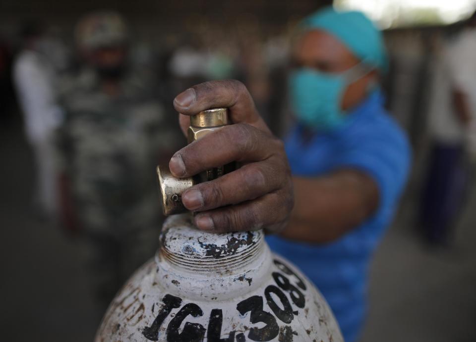 A man waits to refill a medical oxygen cylinder at a charging station on the outskirts of Prayagraj, India, Friday, April 23, 2021. India put oxygen tankers on special express trains as major hospitals in New Delhi on Friday begged on social media for more supplies to save COVID-19 patients who are struggling to breathe. India's underfunded health system is tattering as the world's worst coronavirus surge wears out the nation, which set another global record in daily infections for a third straight day with 346,786. (AP Photo/Rajesh Kumar Singh)