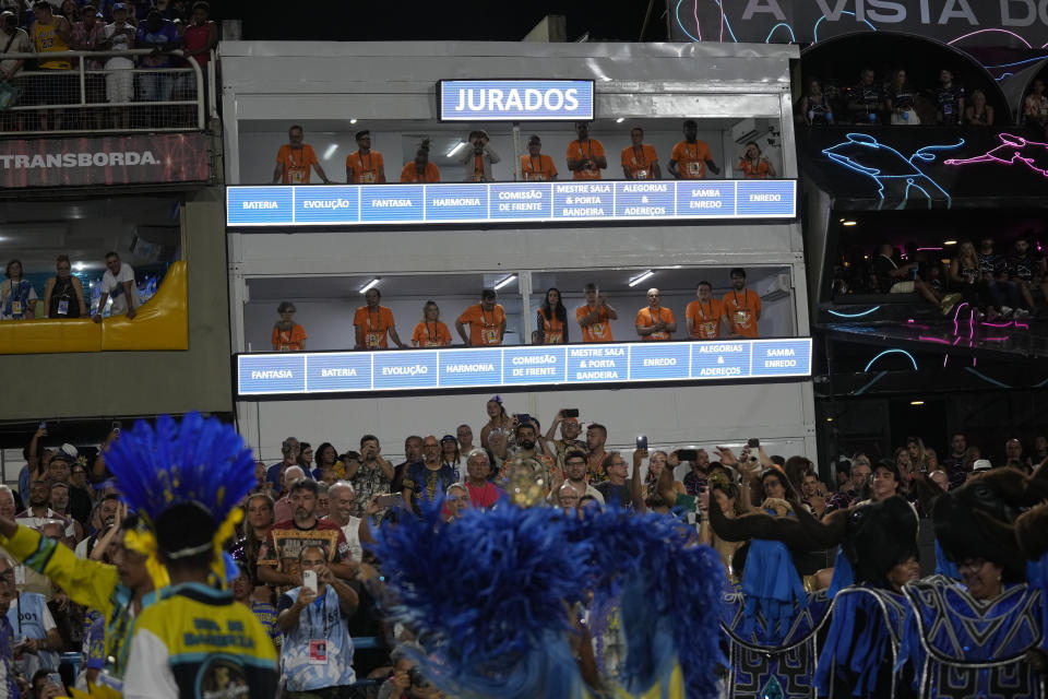 Judges from the Independent League of Samba Schools in Rio de Janeiro, watch and evaluate samba schools parading for Carnival through the Sambadrome in Rio de Janeiro, Brazil, Monday, Feb.20, 2023. (AP Photo/Silvia Izquierdo)