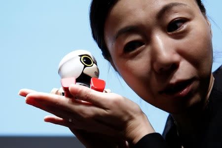 A staff member listens to Toyota Motor Corp's Kirobo Mini robot's voice as she poses with the robot after a news conference in Tokyo, Japan, September 27, 2016. Picture taken on September 27, 2016.REUTERS/Kim Kyung-Hoon