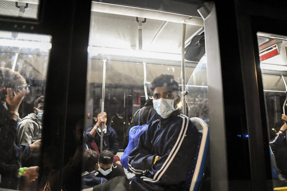 Migrants just disembarked from the Norway-flagged Geo Barents rescue ship carrying 572 migrants, sit on a bus in Catania's port, Sicily, southern Italy, Sunday, Oct. 6, 2022. The Geo Barents, and the German-flagged Humanity1 have been allowed to disembark what the Italian authorities defined "vulnerable people" and minors, while other two ships carrying rescued migrants remained at sea. (AP Photo/Salvatore Cavalli)