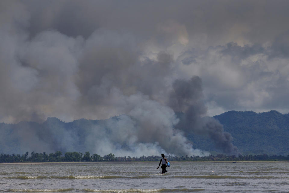 <p>A Bangladeshi boy walks towards a parked boat as smoke rises from across the border in Myanmar, at Shah Porir Dwip, Bangladesh, Thursday, Sept. 14, 2017. (Photo: Dar Yasin/AP) </p>