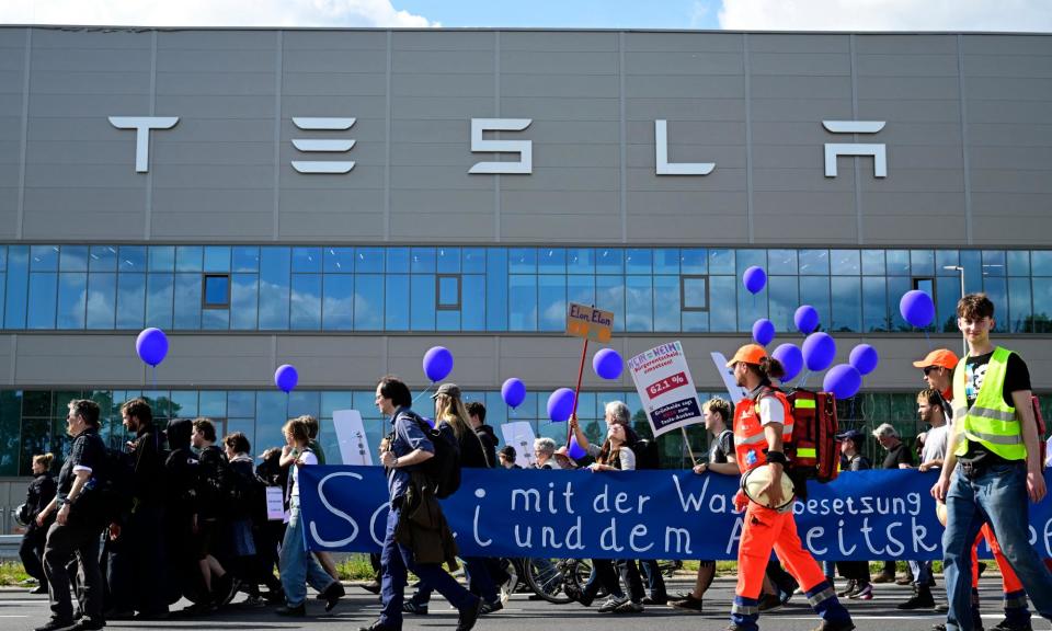 <span>Environmental activists march in front of the Tesla plant in Grünheide, which plans to make 1m EVs a year.</span><span>Photograph: John MacDougall/AFP/Getty Images</span>