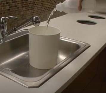 Someone pouring ammonia into a bucket.