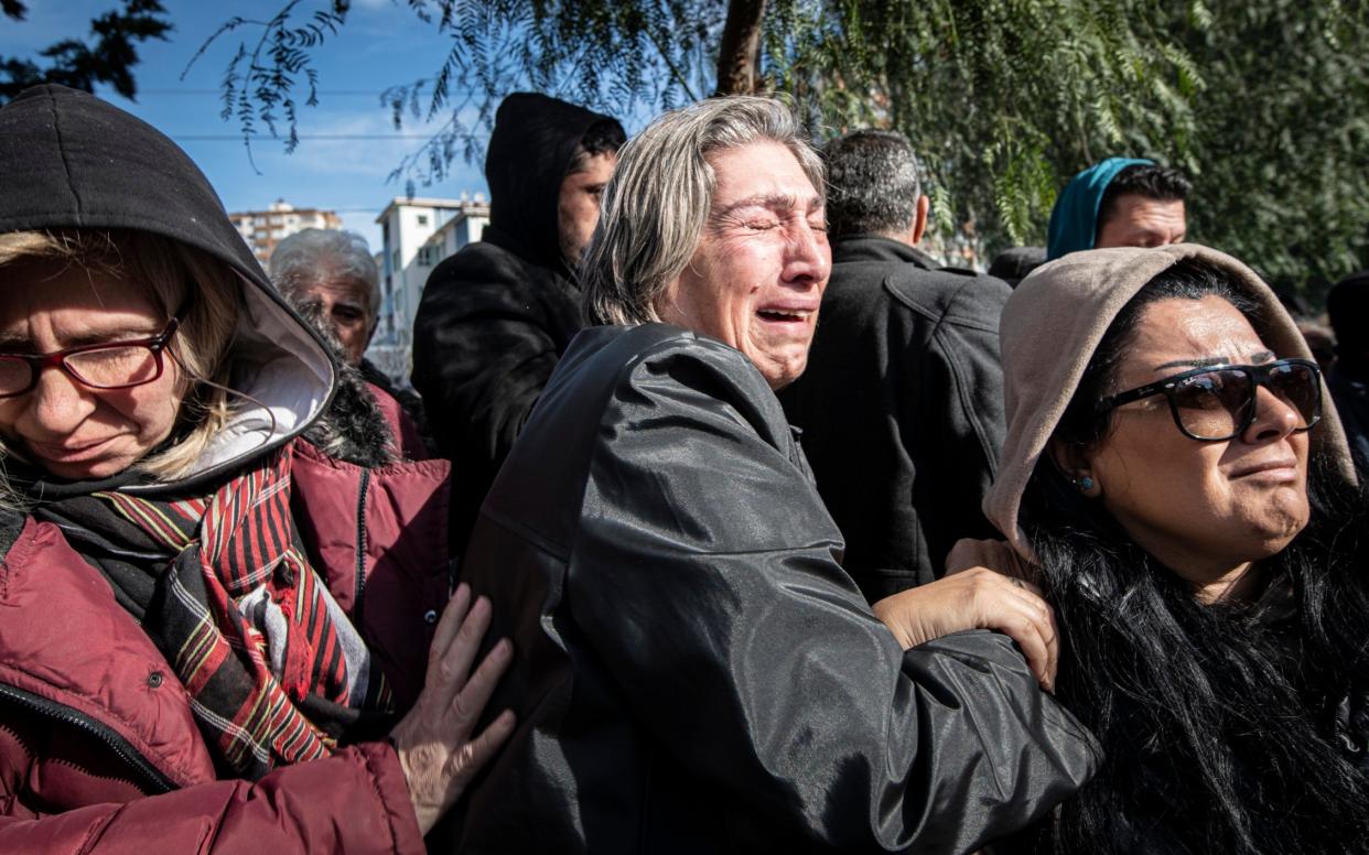 Durdane Arnas, centre, waits for news of her missing family outside a collapsed apartment block in Adana - Simon Townsley/The Telegraph