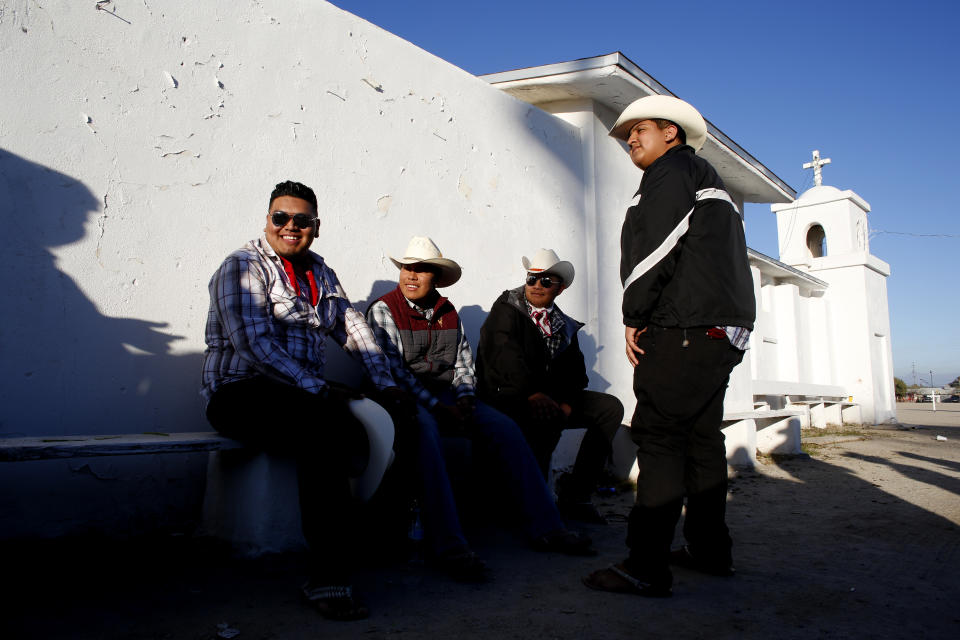 In this Feb. 8, 2020, photo, men gather outside of the Our Lady of Guadalupe church in the town of Guadalupe, Ariz., near Phoenix. Founded by Yaqui Indian refugees from south of the border more than a century ago, the town named for Mexico's patron saint, is proud of its history but wary of outsiders as it prepares for the 2020 Census count its leaders hope will help better fund a $12 million budget to fill potholes and mend aging sewage lines. (AP Photo/Dario Lopez-MIlls)