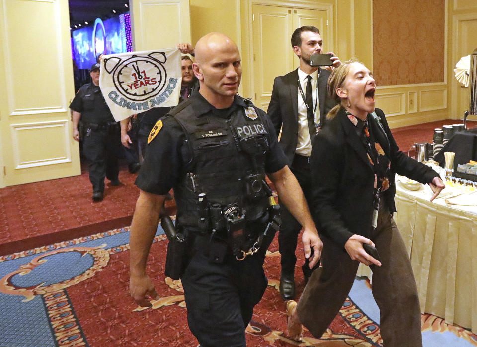 About 25 protesters are escorted by police after interrupting a energy summit conference where U.S. Energy Secretary Rick Perry spoke Thursday, May 30, 2019, in Salt Lake City. Perry says the Trump administration is committed to making fossil fuels cleaner rather than imposing "draconian" regulations on oil, gas and coal. Perry made his remarks during a speech at an energy conference in Salt Lake City hosted by Utah Gov. Gary Herbert. (AP Photo/Rick Bowmer)