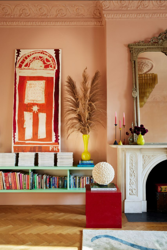 living room with pink walls, white fireplace and  blue console with books