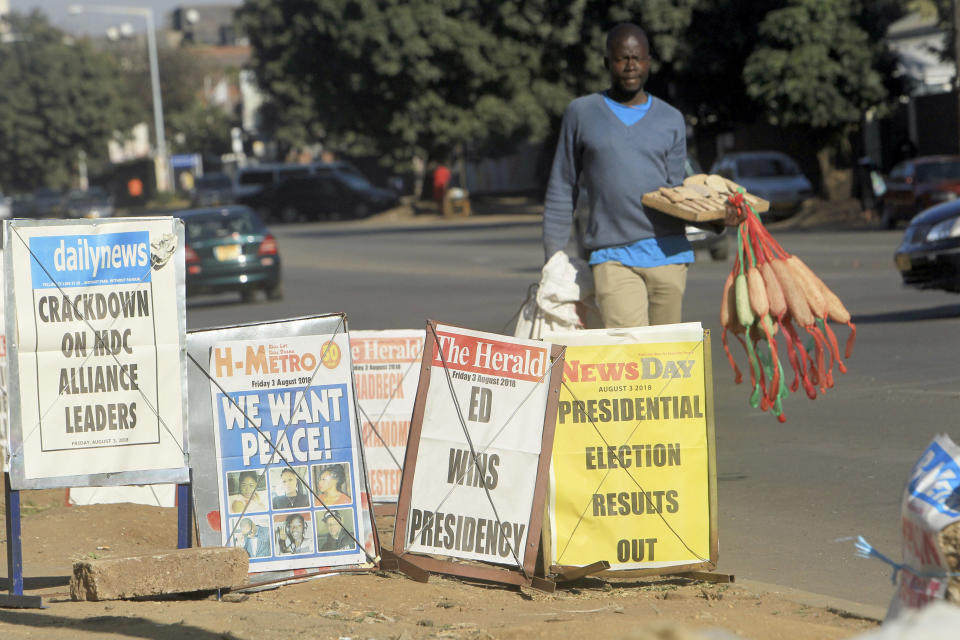 A vendor sells sponges near newspaper headlines on the streets of Harare, Friday, Aug. 3, 2018. Zimbabwe's President Emmerson Mnangagwa won an election Friday with just over 50 percent of the ballots as the ruling party maintained control of the government in the first vote since the fall of longtime leader Robert Mugabe (AP Photo/Tsvangirayi Mukwazhi)